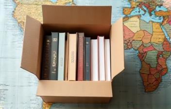 Shipping box filled with books and packaging material, next to a map